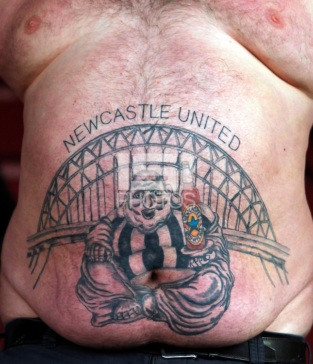 A Newcastle United fan sports a large tattoo on his stomach
